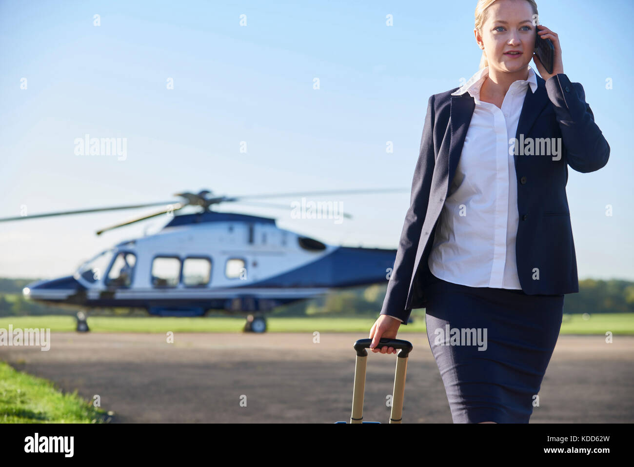 Imprenditrice a piedi da elicottero mentre parli al telefono cellulare Foto Stock