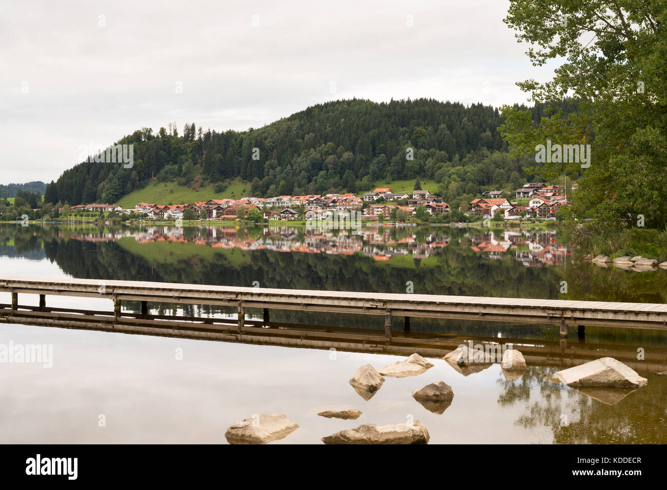 La città di Hopfen am vedere riflesso nell'acqua ancora della Hopfensee, Ostallgaeu, Baviera, Germania Foto Stock