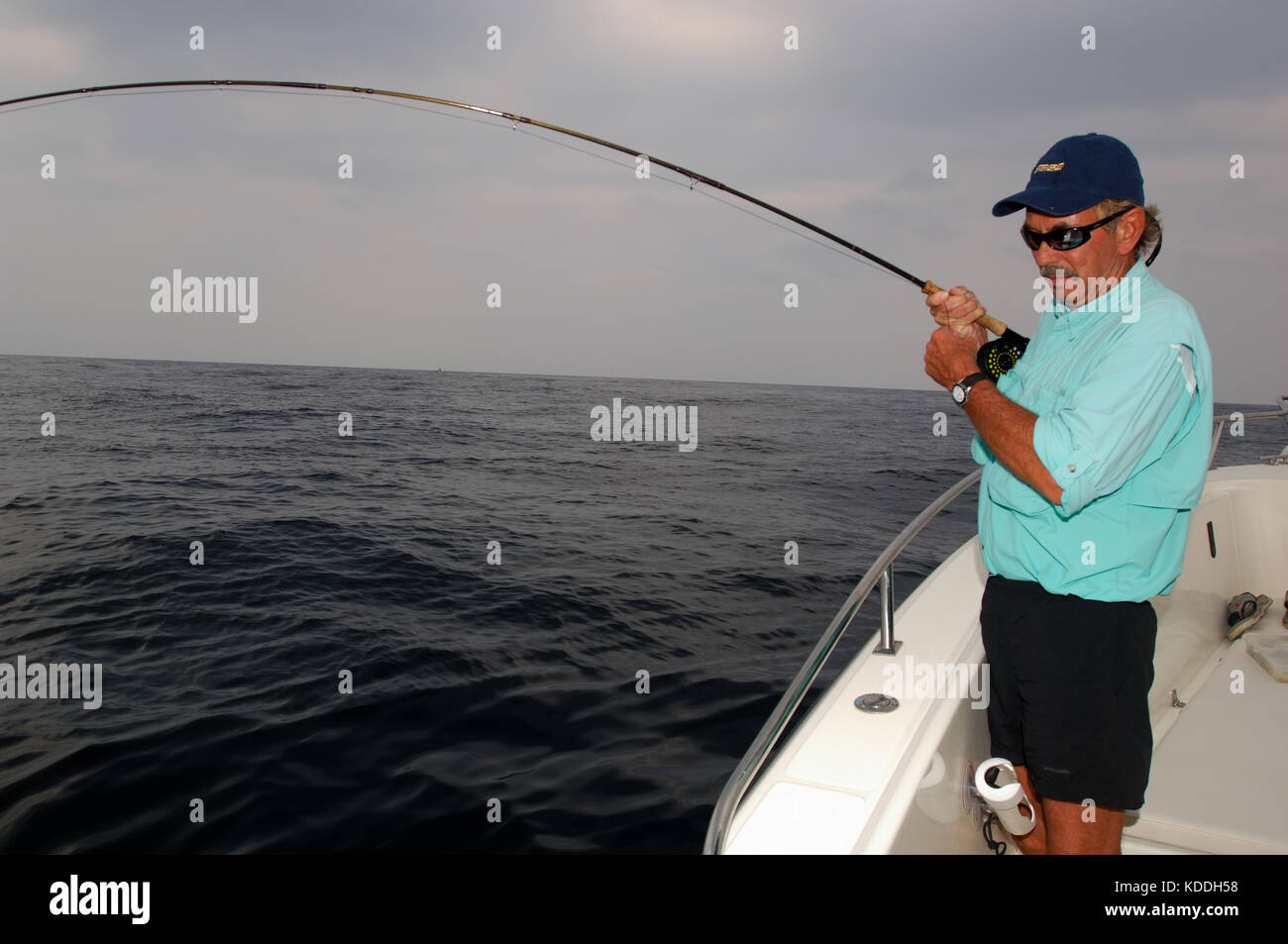 Un pescatore a mosca combatte contro un grande pesce mentre la pesca dagli impianti offshore di Freeport, Texas Foto Stock