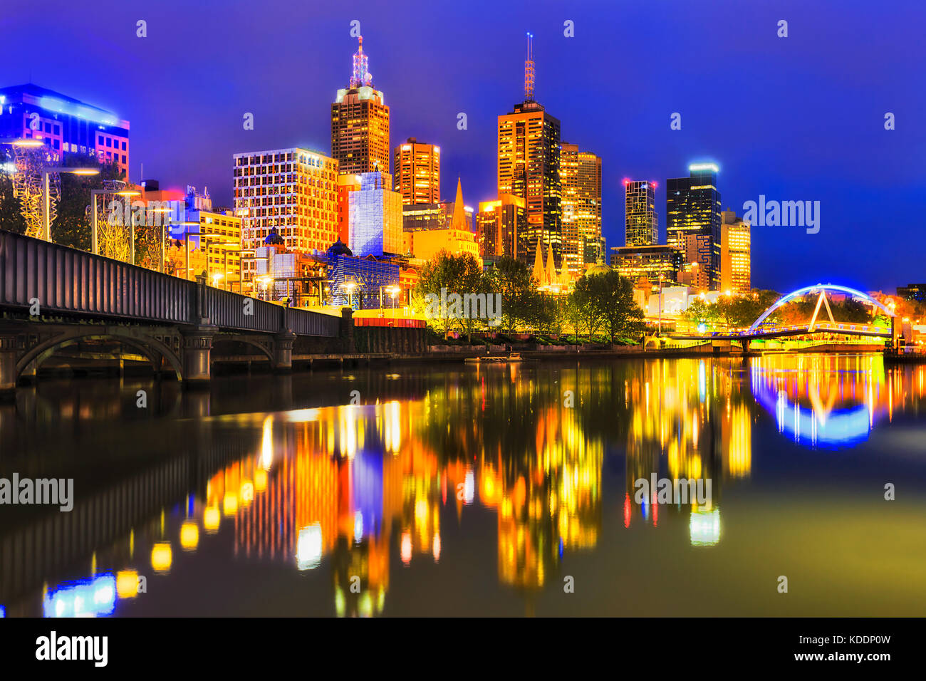 Illuminato città di Melbourne luci riflettenti ancora in acque del fiume Yarra tra 2 piedi ponti a sunrise. Foto Stock