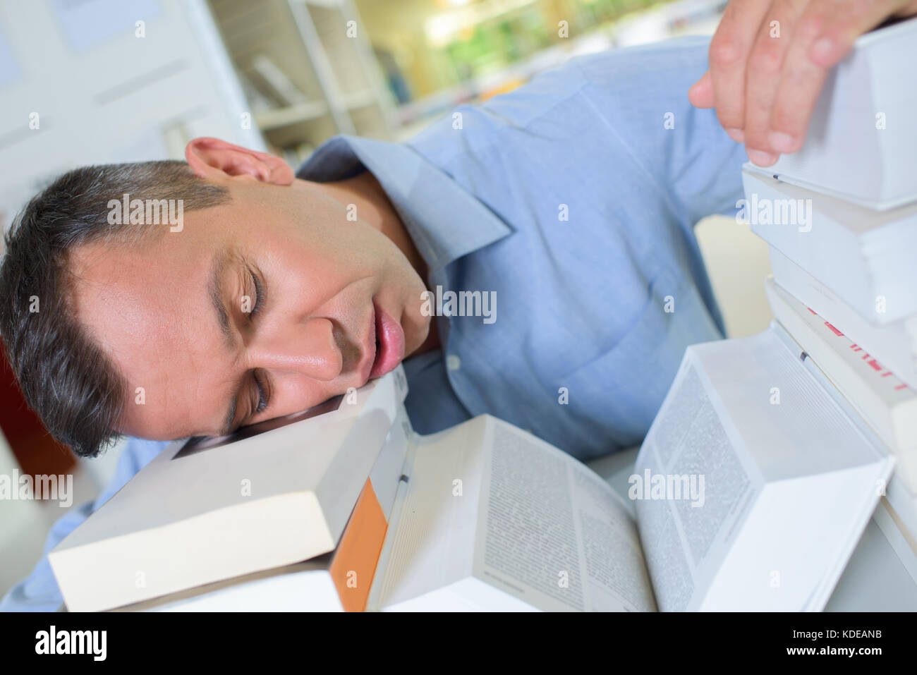 Uomo di dormire su libri Foto Stock