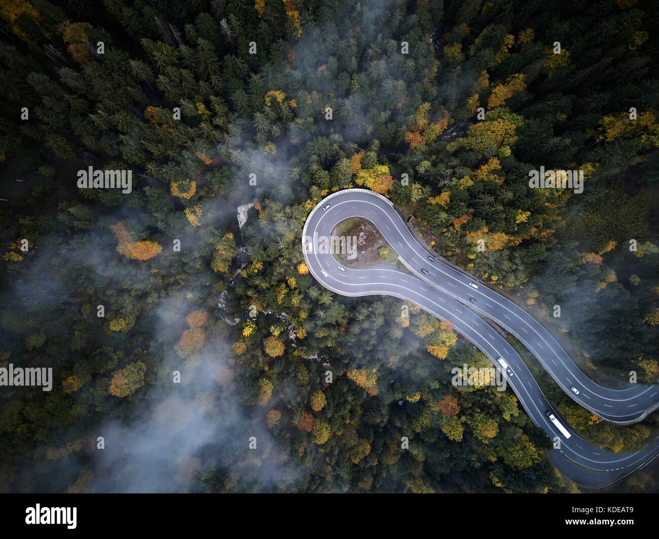 Street da sopra attraverso una foresta di nebbia in autunno, vista aerea volando attraverso le nuvole con la nebbia e alberi Foto Stock
