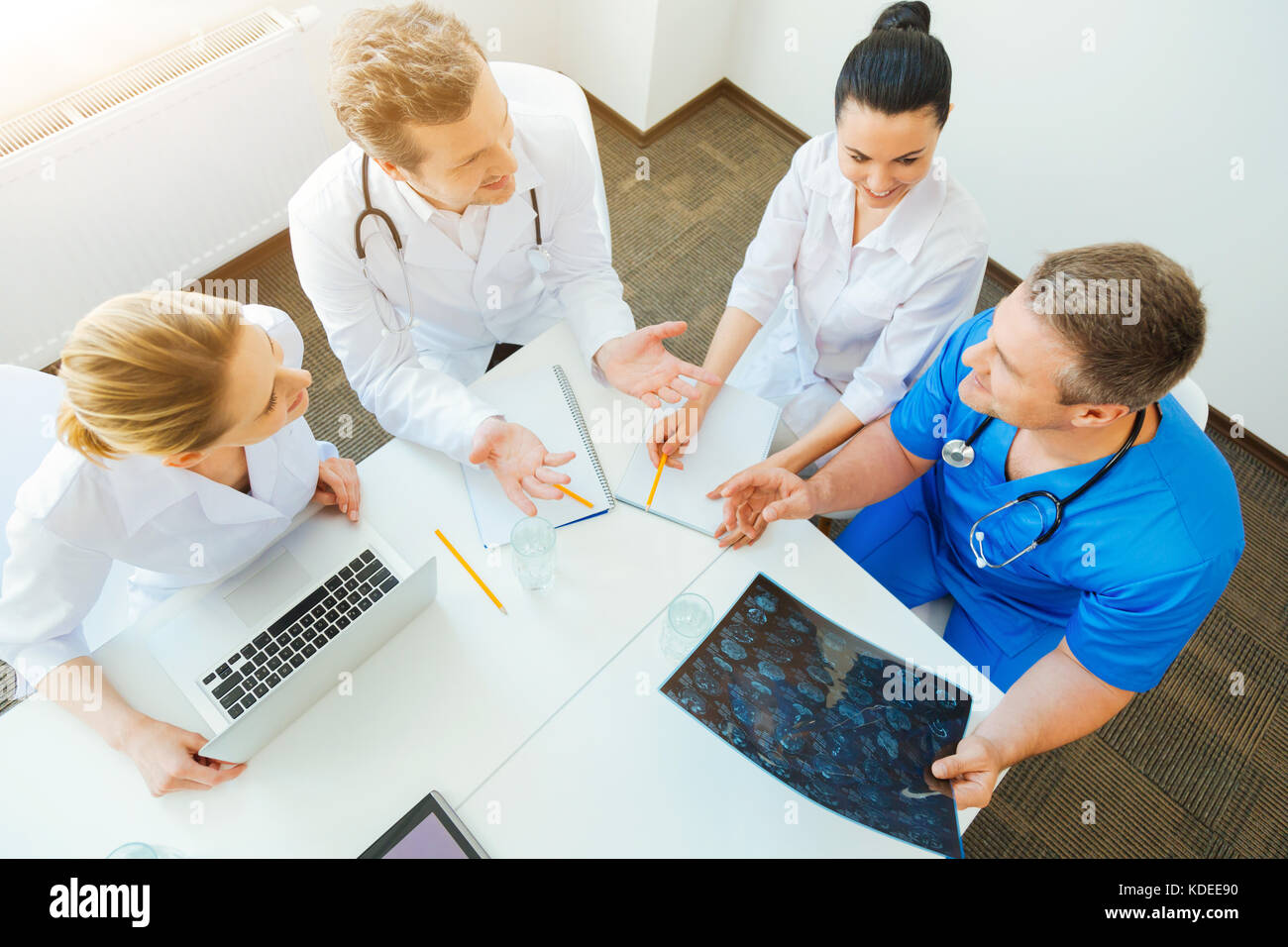 Quattro Dottori chiacchierano sopra x ray scansione foto del paziente Foto Stock