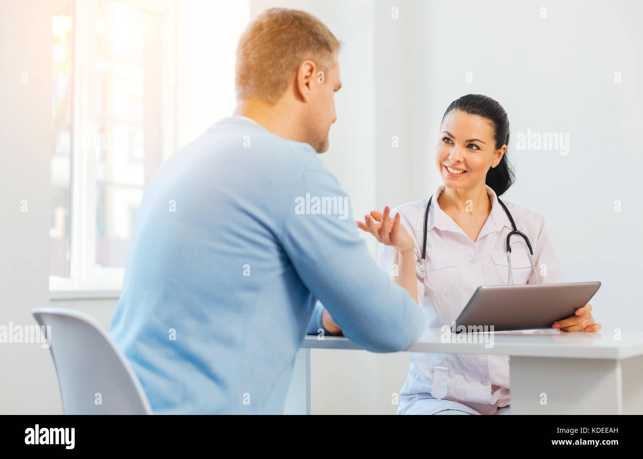 Posso aiutarvi a. positivo medico professionale esaminando il suo paziente mentre si utilizza il tablet e lavorando in ospedale Foto Stock