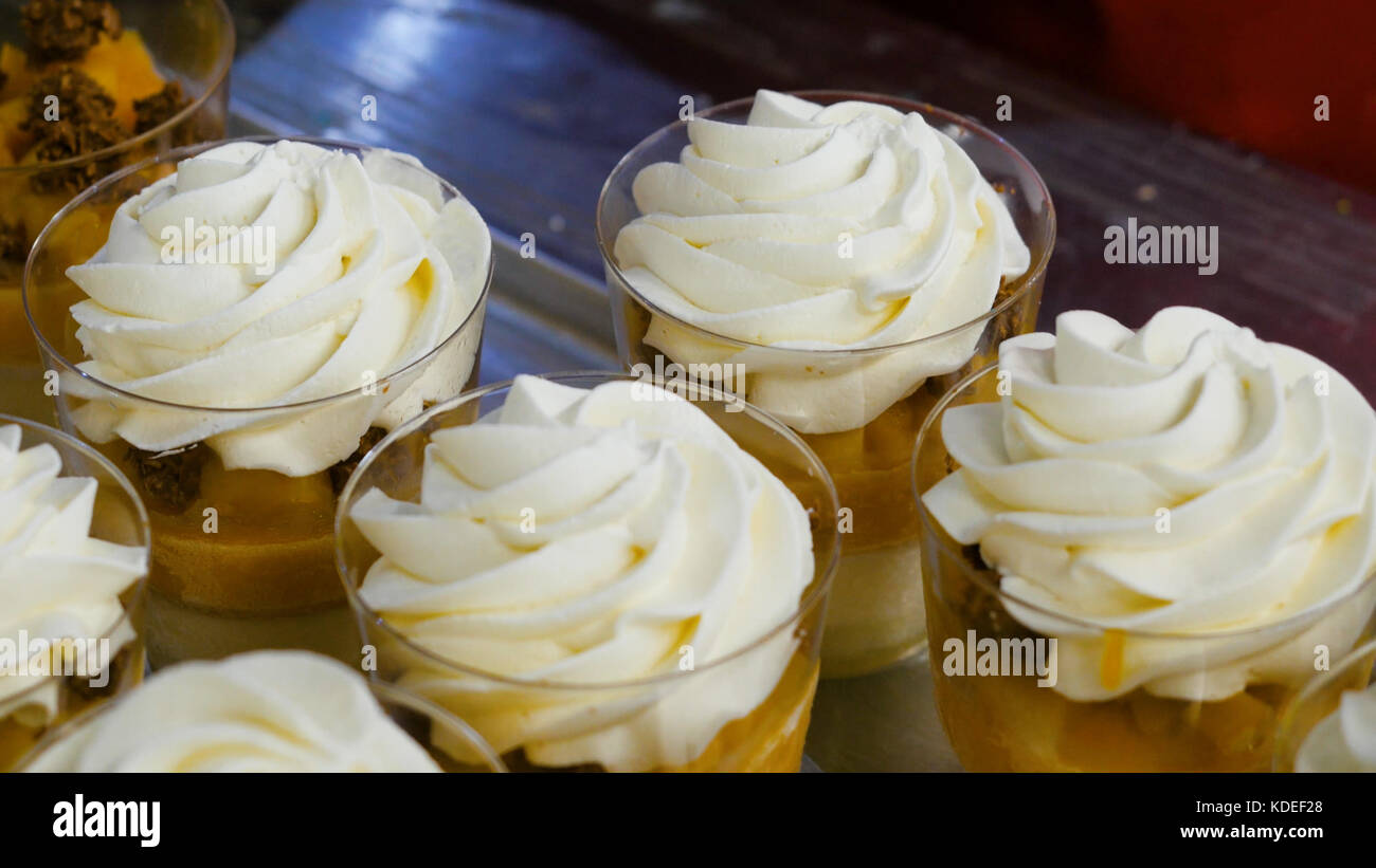 Gustoso dessert con salsa di ciliegie in bicchiere. Dessert alla frutta con panna montata, menta e muesli. Frutta fresca su panna montata. Foto Stock