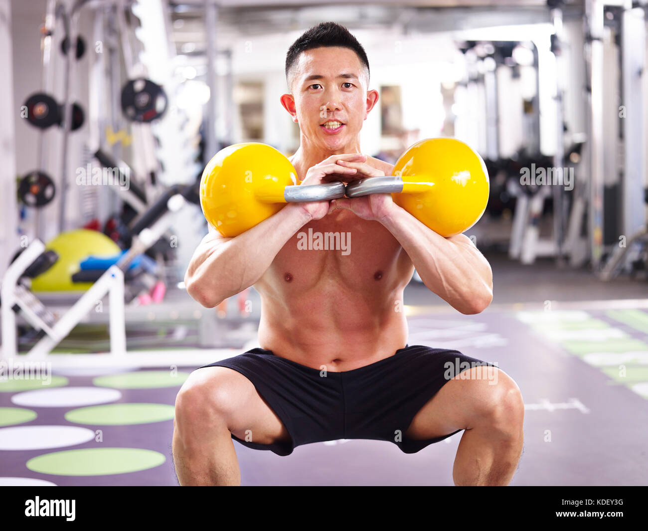 Maschio asiatici bodybuilder che lavora fuori in palestra con bollitore campane. Foto Stock