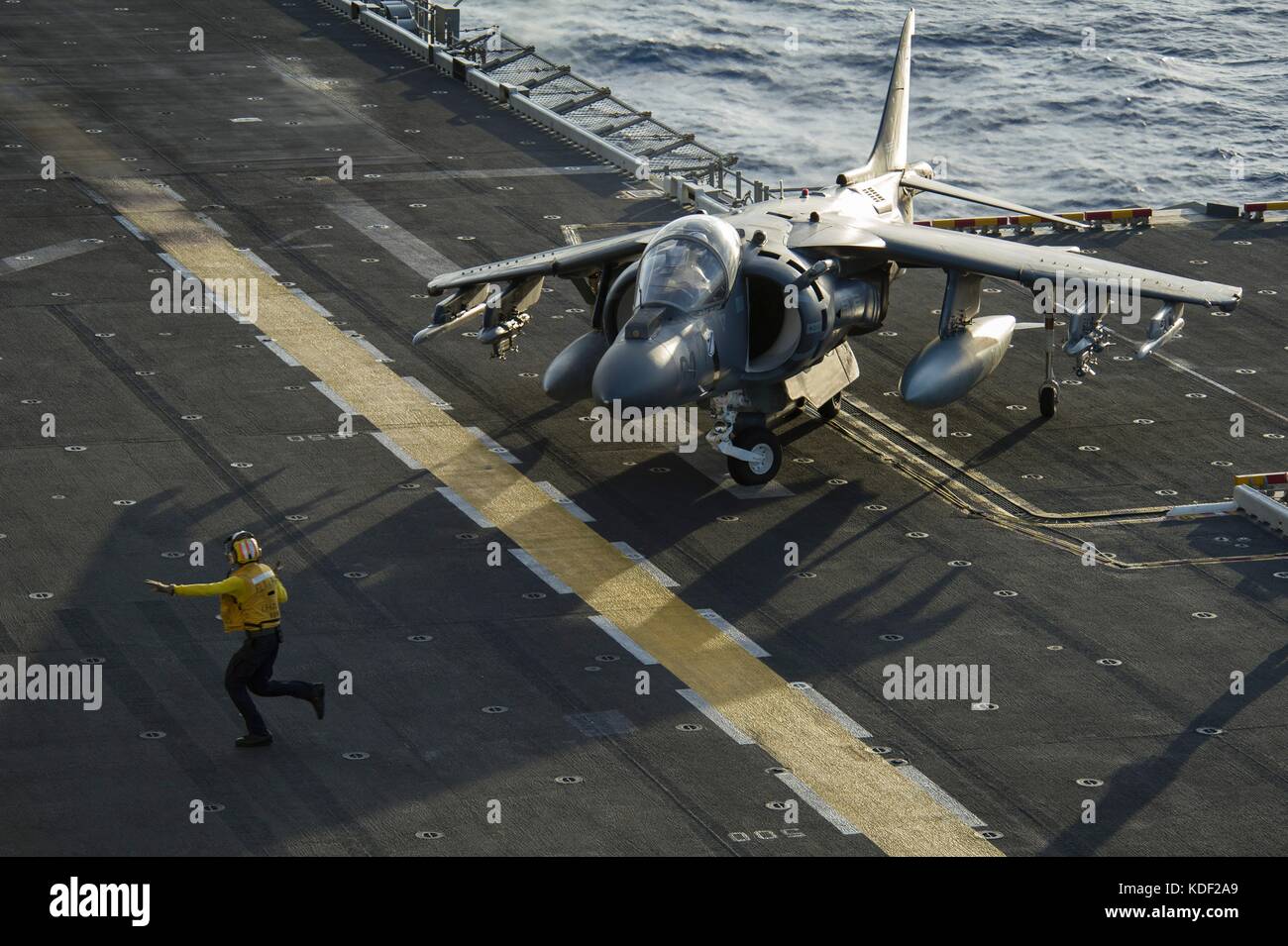 Un marinaio statunitense dirige un aereo d'attacco al suolo AV-8B Harrier II del corpo dei Marines che atterra sulla piattaforma di volo a bordo della nave d'assalto anfibia USS America della Marina americana il 16 luglio 2017 nell'Oceano Pacifico. (Foto di Ramon Go via Planetpix) Foto Stock