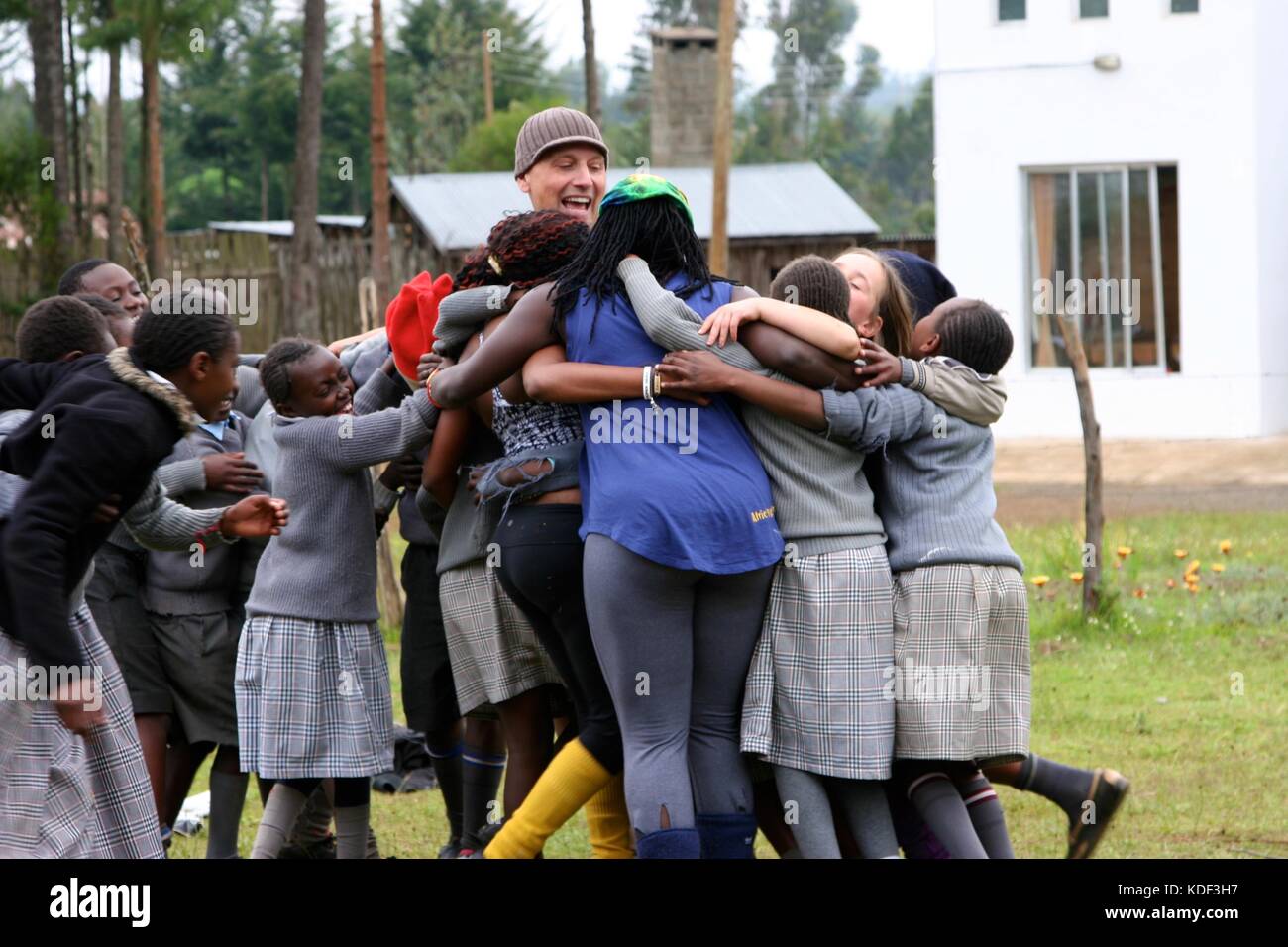 Scuola africana bambini abbracciando caucasica turisti di volontariato in un orfanotrofio in Kenya Foto Stock