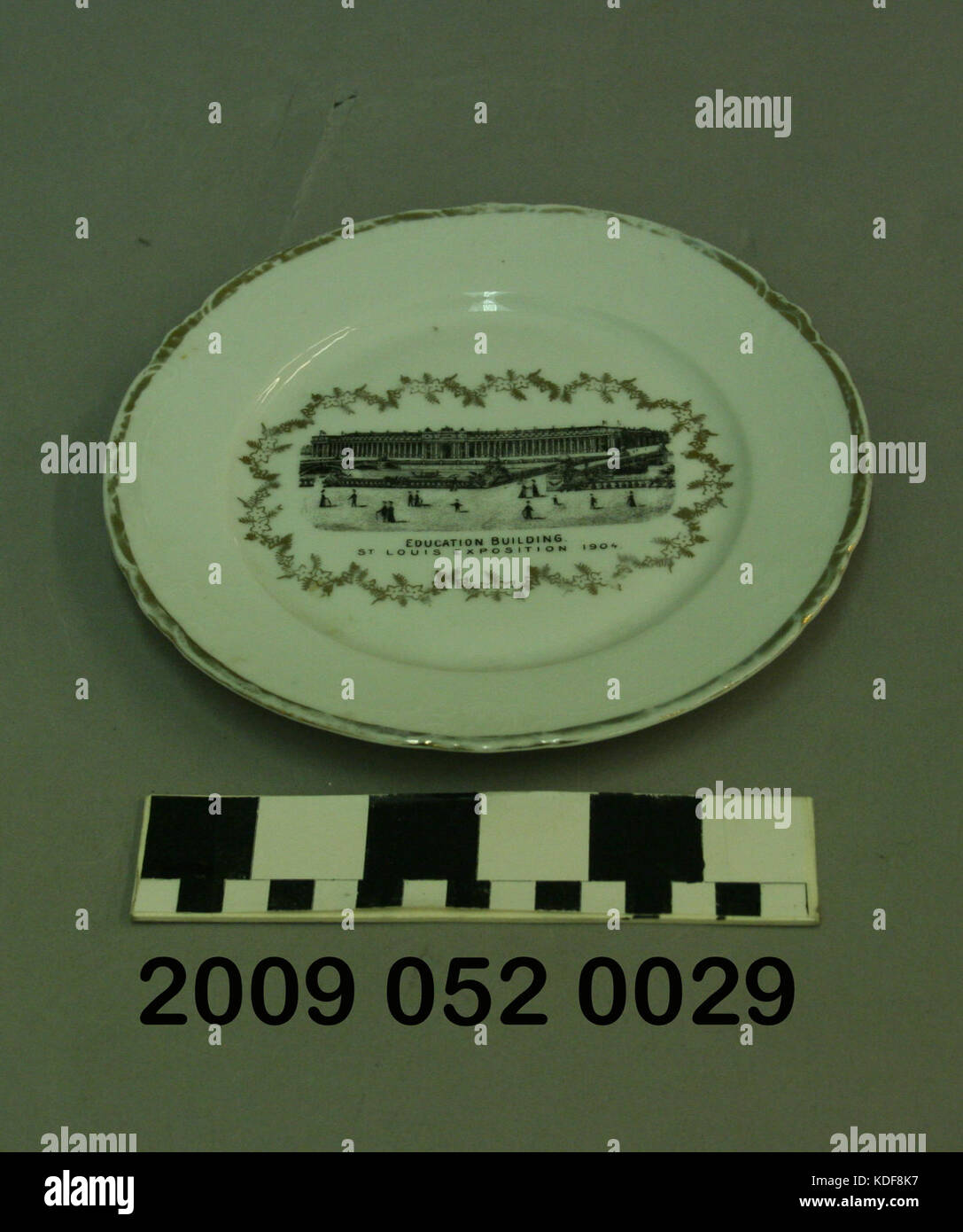 Un piccolo piatto di ceramica bianca con un'immagine nera del Palazzo dell'Educazione. Il piatto mostra la raffinata maestria artigianale e funge da elemento decorativo di importanza culturale e storica, riflettendo l'estetica del design del tempo. Foto Stock