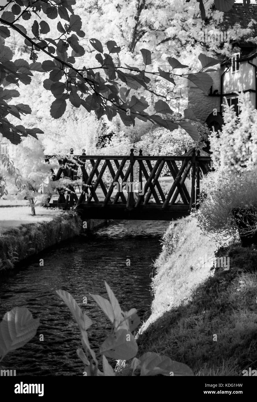 Una immagine infrarossa di una passerella su un millstream. Foto Stock
