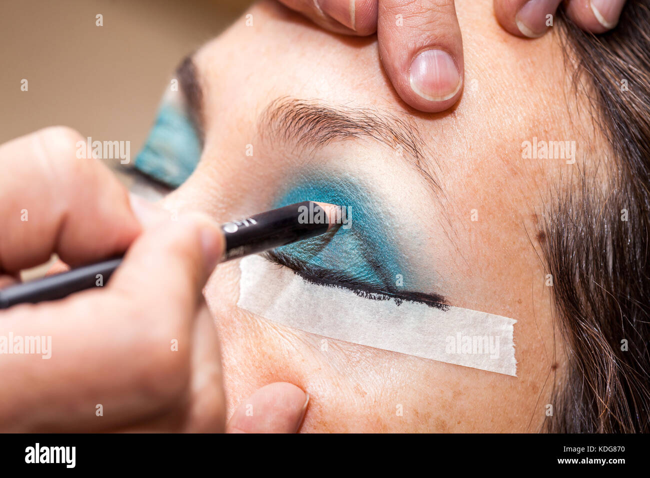 Make up Artist usando del nastro adesivo protettivo per la creazione di occhi di gatto Foto Stock