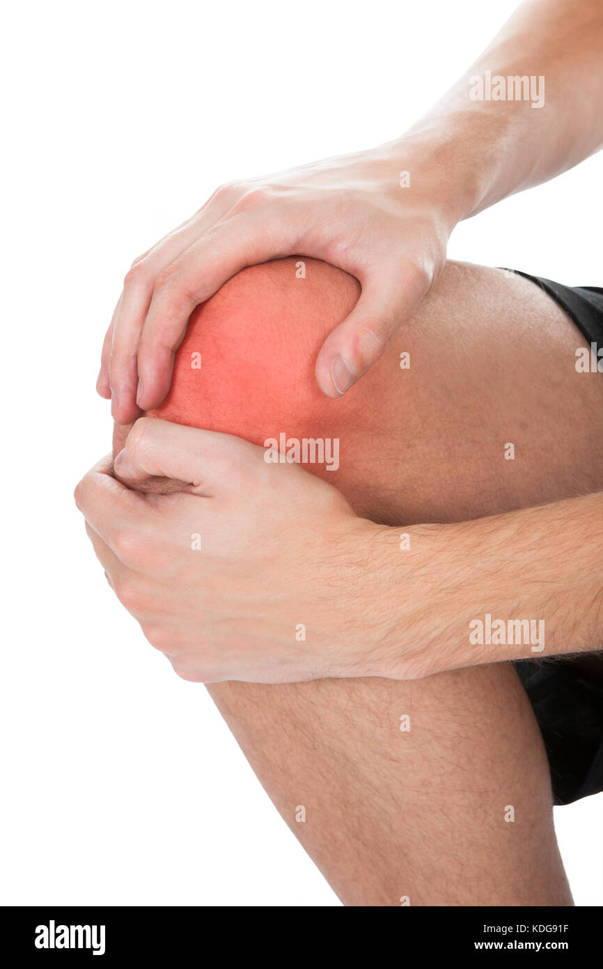 Close-up di uomo che soffre di infortunio al ginocchio su sfondo bianco Foto Stock