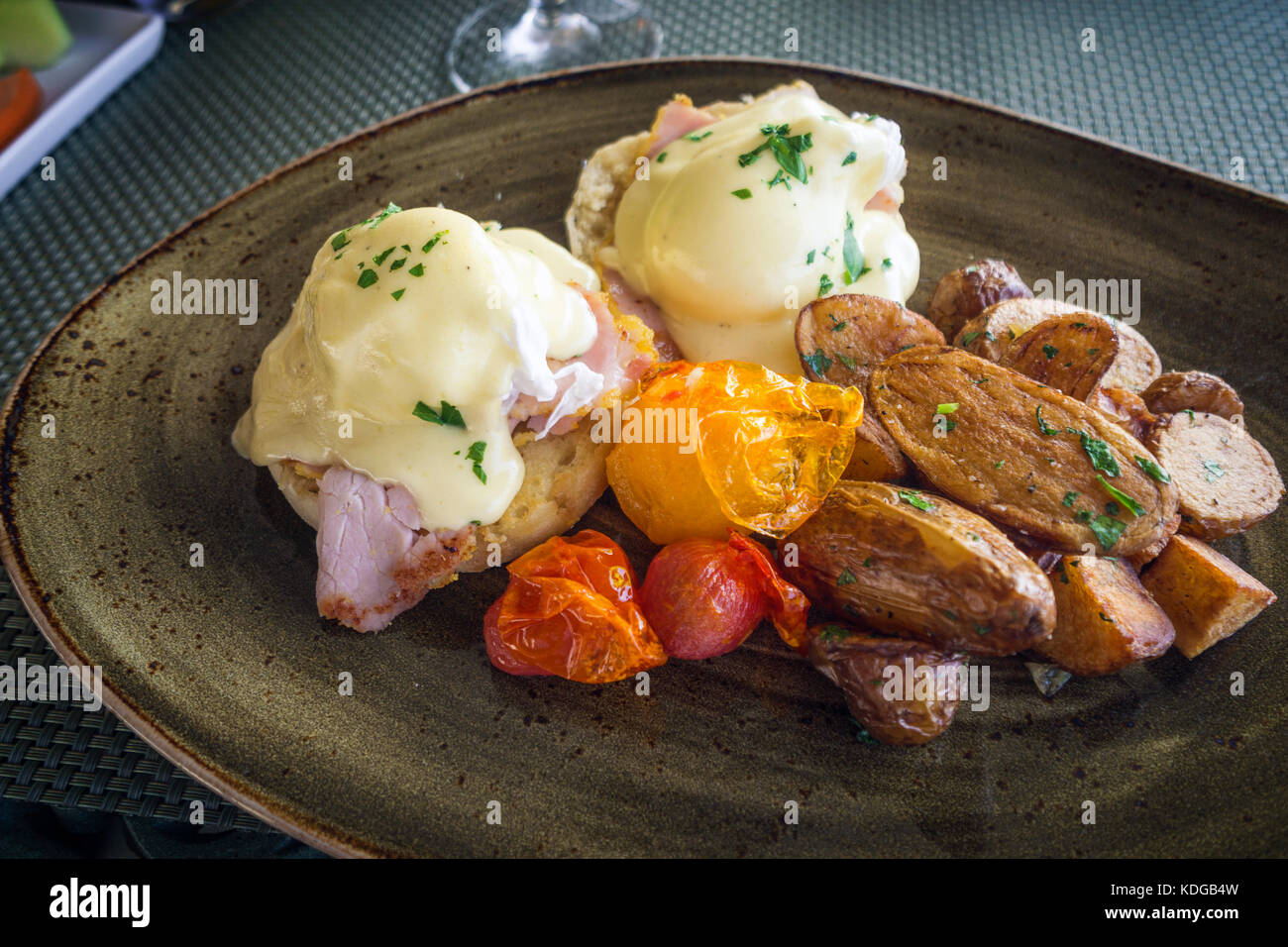 Deliziosa benedetto uova servite con patatoes cotti al forno e pomodori sulla piastra scuro Foto Stock