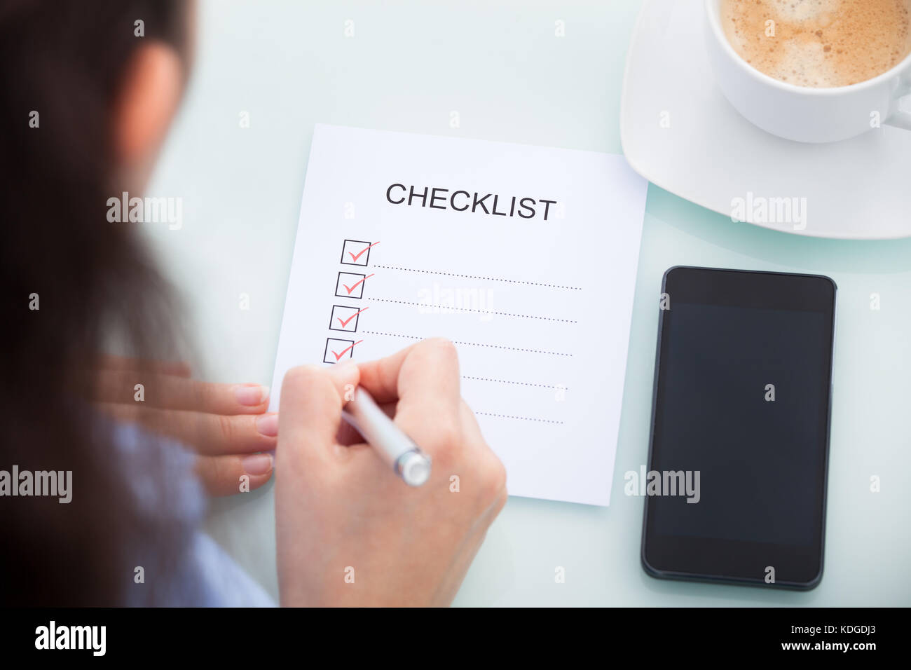Angolo di alta vista di una imprenditrice marcatura sulla lista di controllo al banco Foto Stock