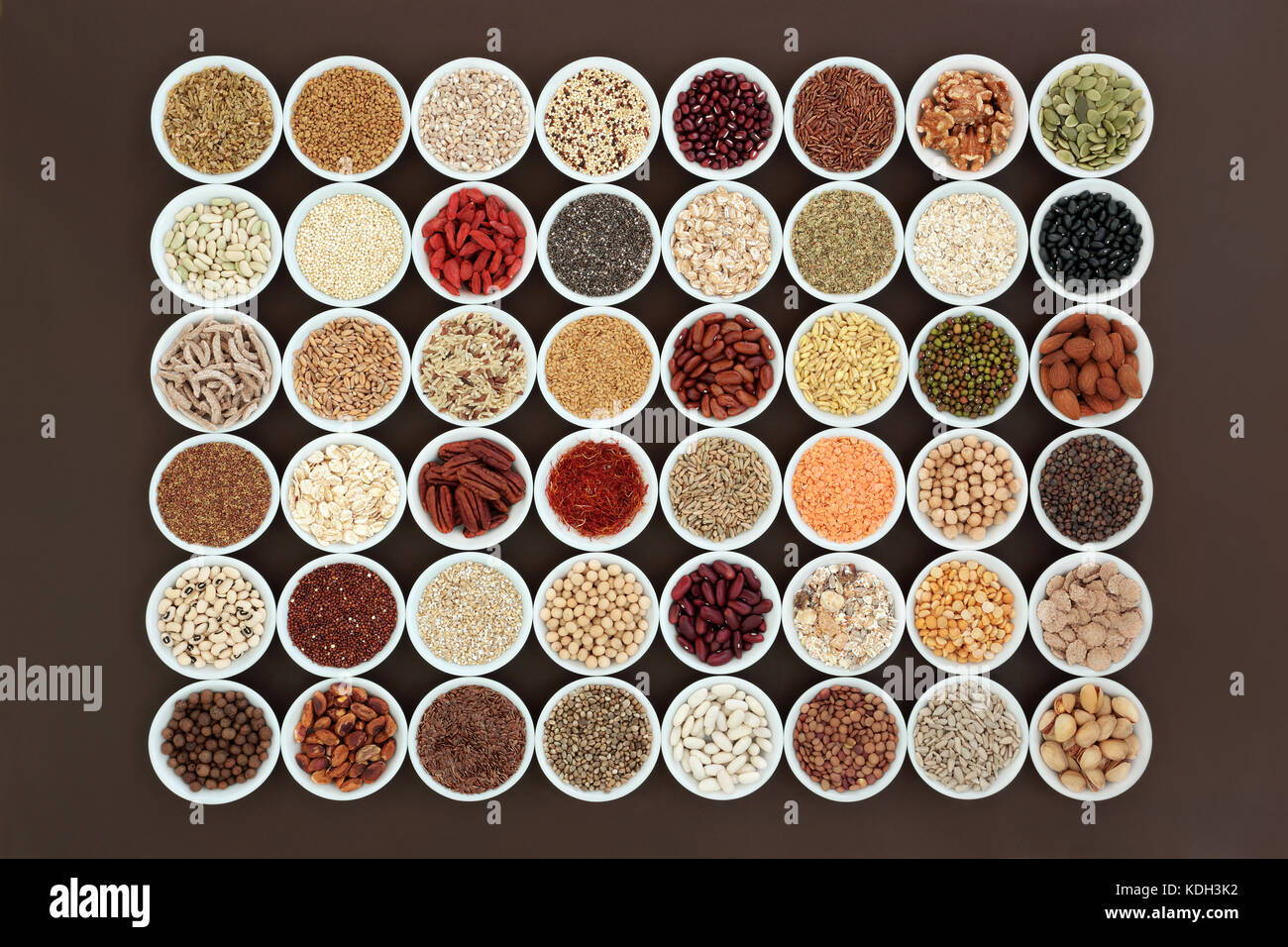 Una sana con alto livello di fibre alimentari dietetici concetto in porcellana ciotole con frutta, legumi, noci, semi, cereali e grano. Foto Stock