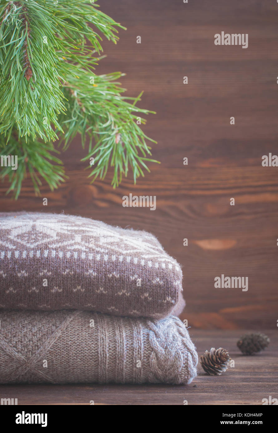 Pila di maglia beige abbigliamento invernale su sfondo di legno, maglioni, maglieria, spazio per il testo Foto Stock