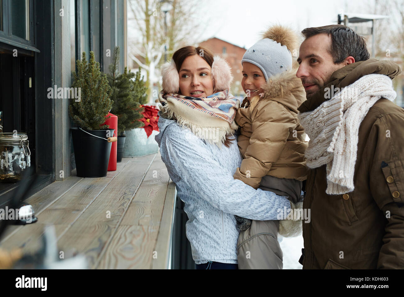 Coppia giovane e la loro piccola figlia di andare a comprare qualcosa in chiosco con contatore di legno Foto Stock