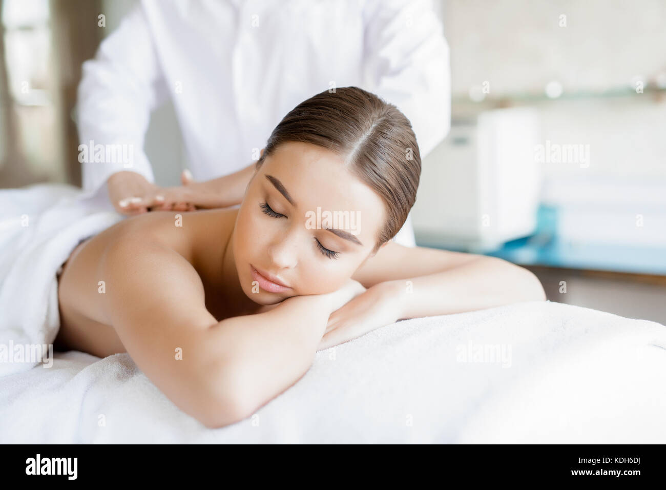 Rilassata giovane donna giacente in spa salone e godendo professional massaggio corpo Foto Stock