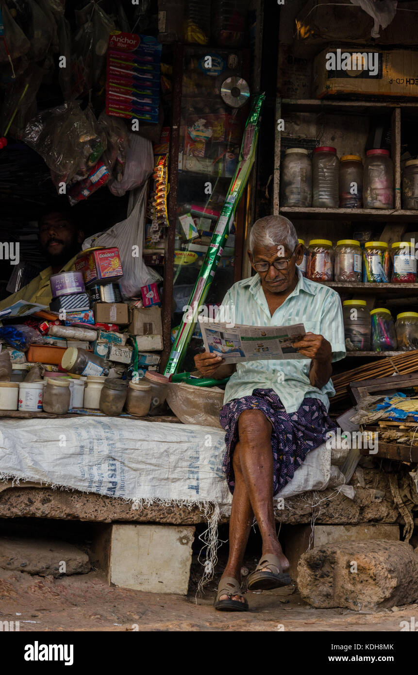 Un uomo leggendo un giornale nel suo negozio di fort kochi Foto Stock