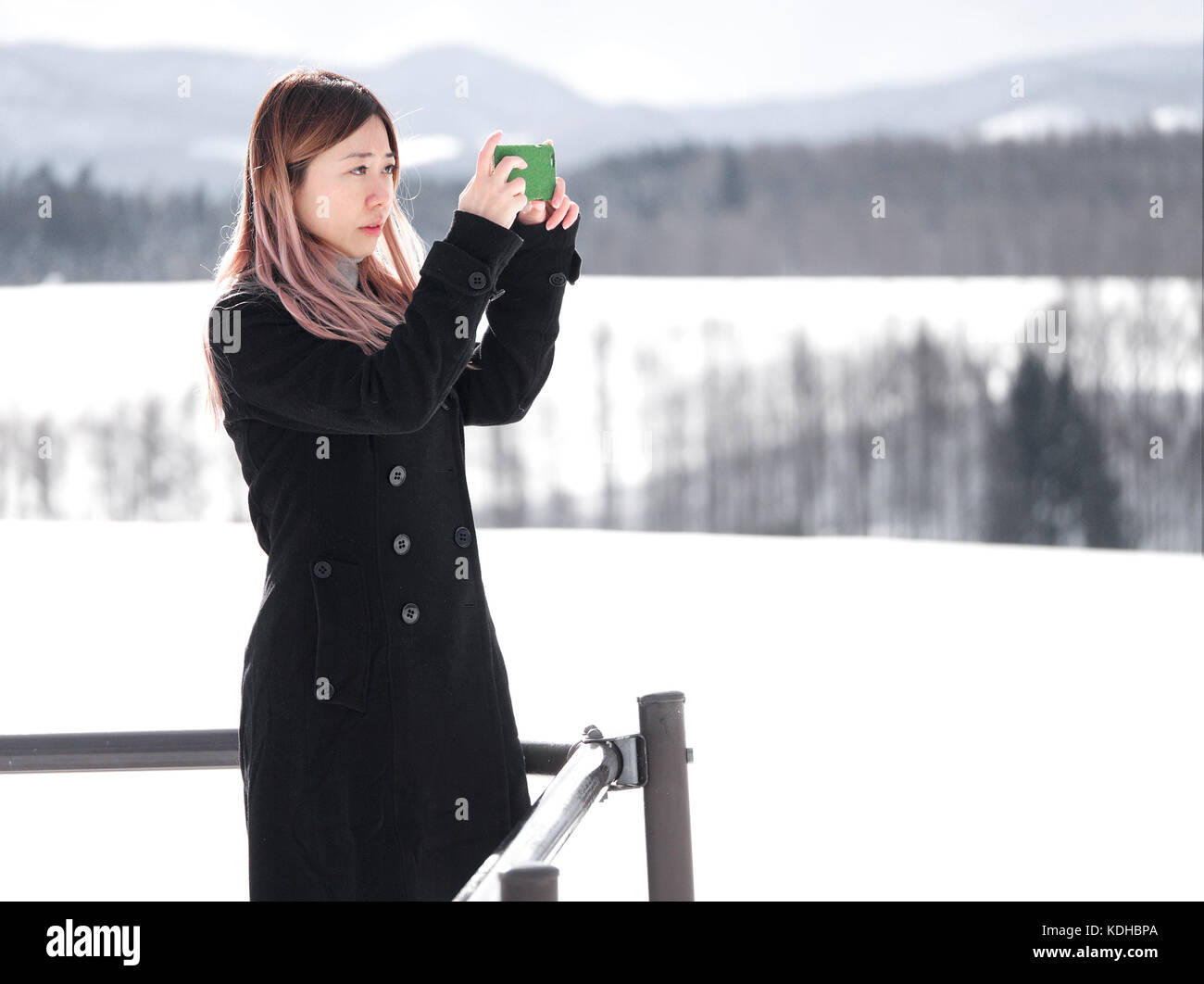 Asian Chinese Tourist scattare foto con un cellulare fotocamera a Biei, Hokkaido, Giappone, in inverno Foto Stock