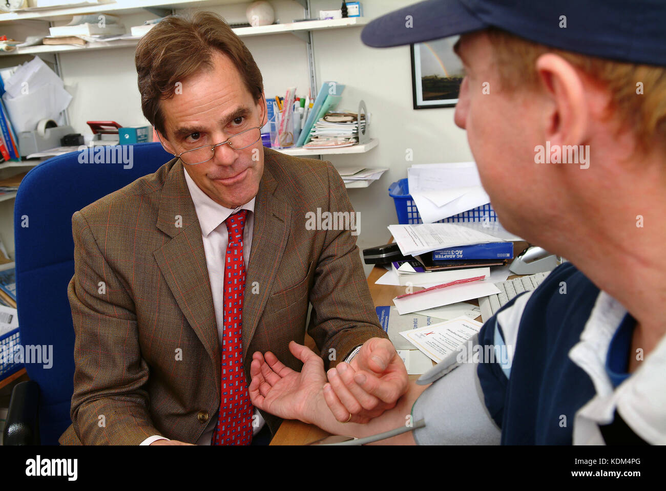 Dr.Robert Muir (Il Lodge chirurgia, Chippenham) tenendo la pressione sanguigna di un paziente. Foto Stock