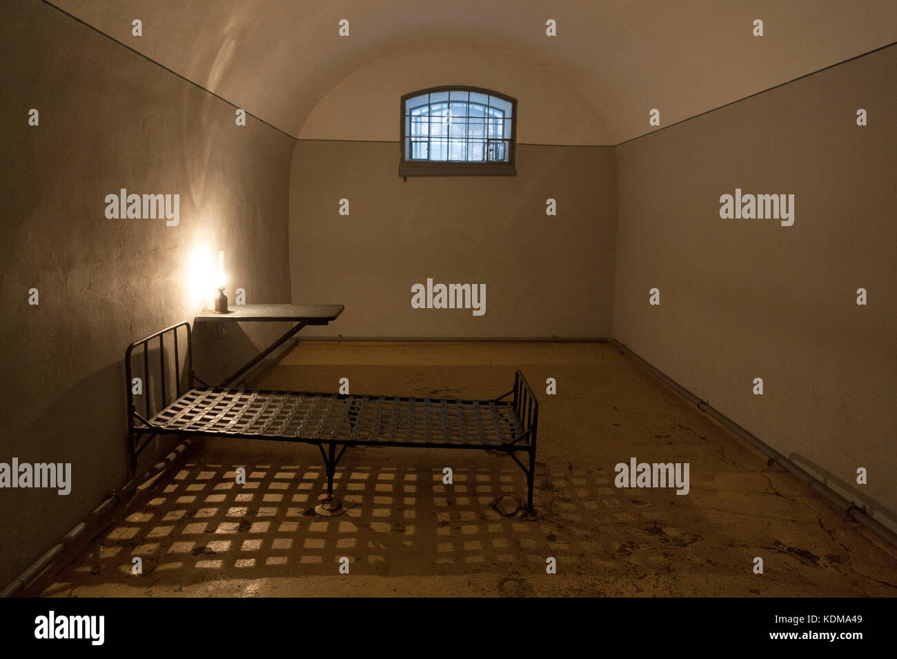 Vecchia Prigione di interno della cellula nella prigione della fortezza di Pietro e Paolo a San Pietroburgo, Russia, con una piccola finestra, lampada vintage e letto di ferro. Foto Stock