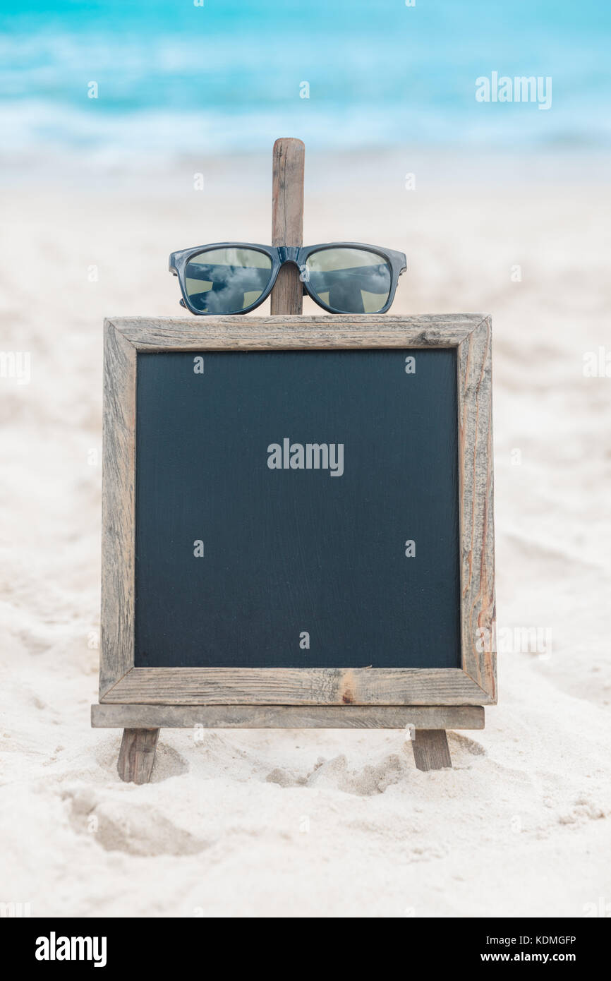 Chalk board con occhiali da sole nella sabbia sulla spiaggia tropic sfondo esotico Foto Stock