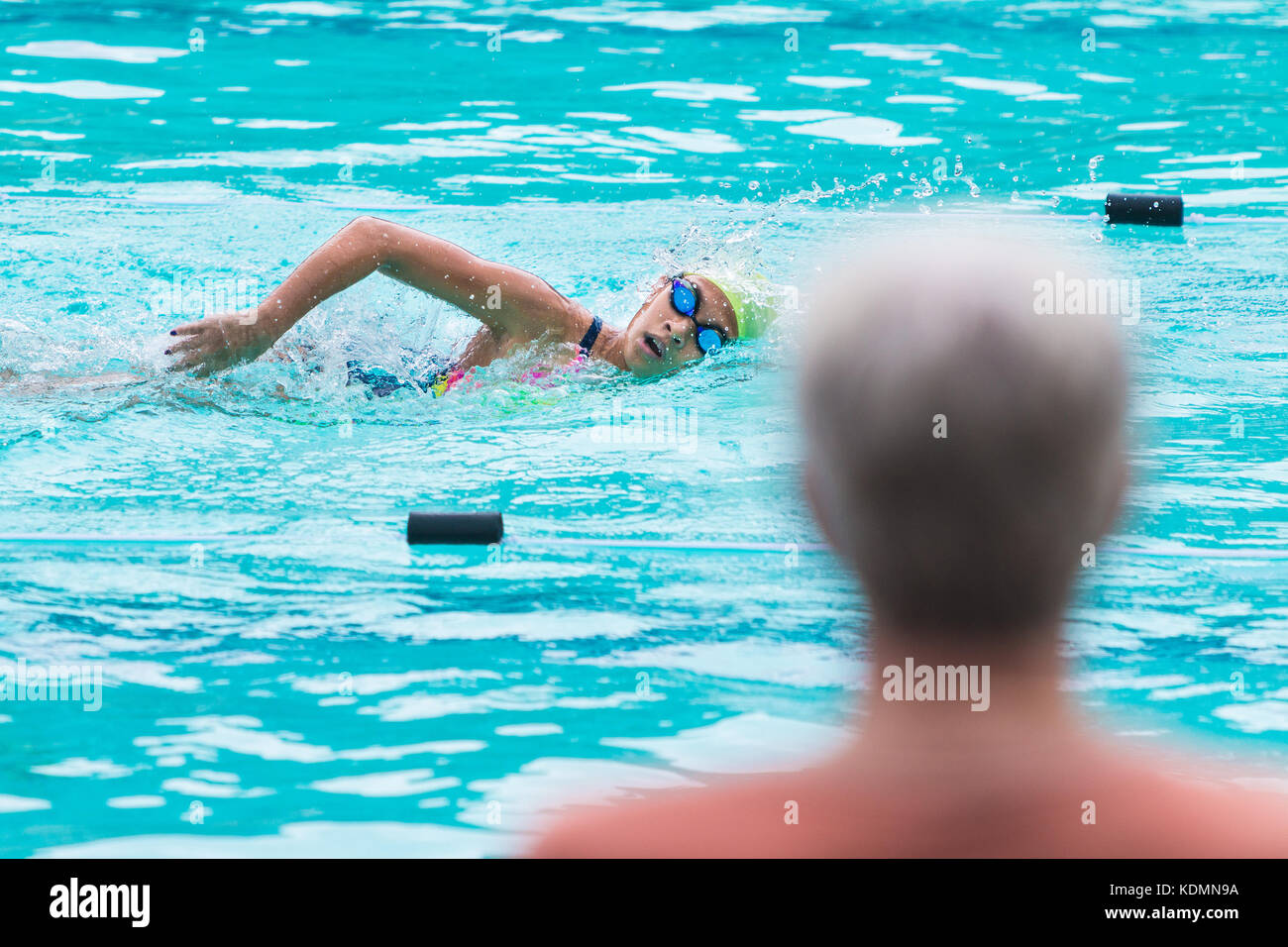 Chiang Mai, Thailandia - 11 ottobre 2017 - Un genitore orologi una giovane femmina nuotatore nuoto nella corsa di freestyle presso una scuola di nuoto in piscina a Chiang Mai, Foto Stock