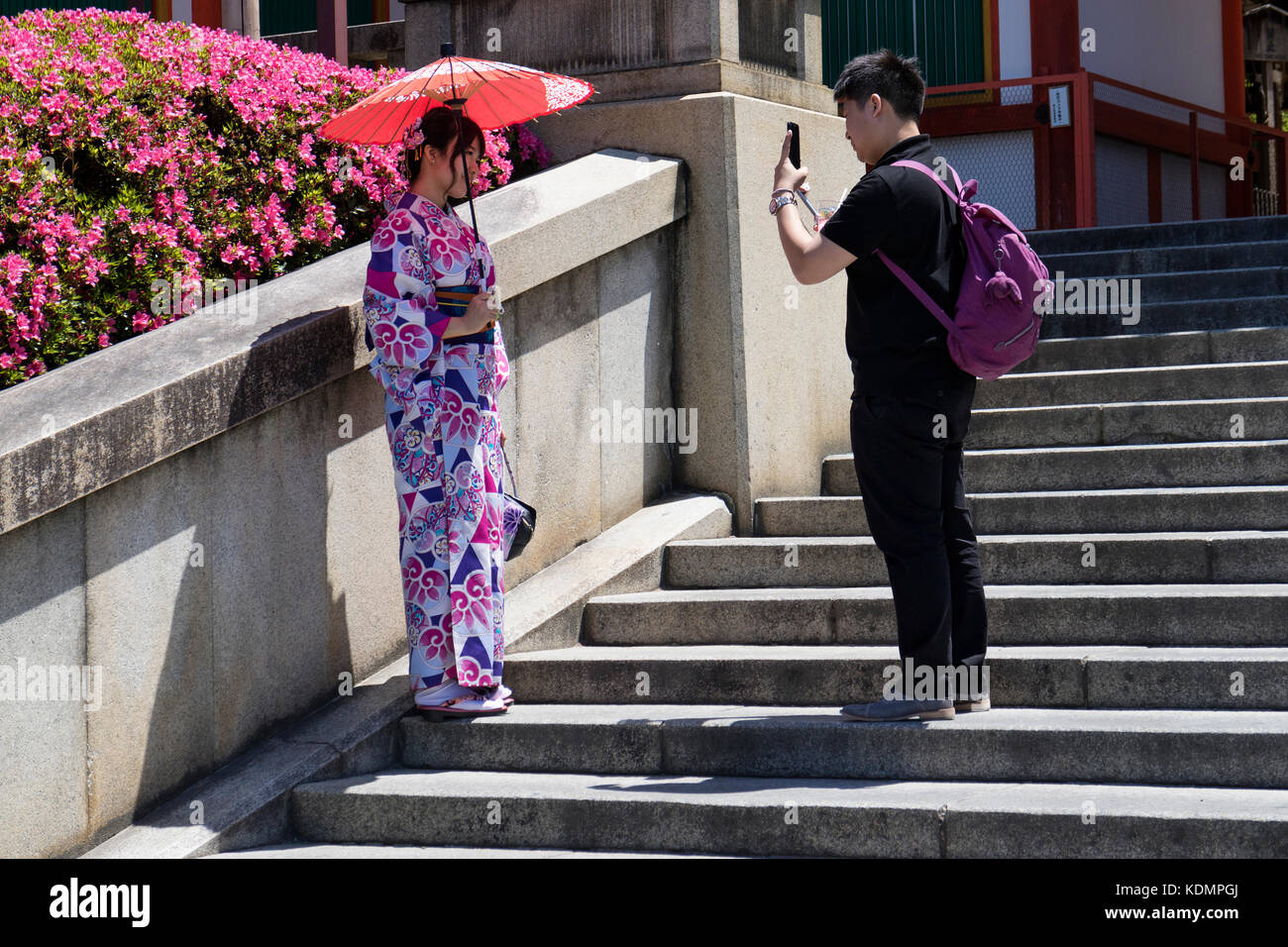 Kyoto, Giappone - 19 maggio 2017: Una ragazza tradizionale vestita in kimono con ombrellone viene fotografata alle scale del santuario Yasaka jinja Foto Stock