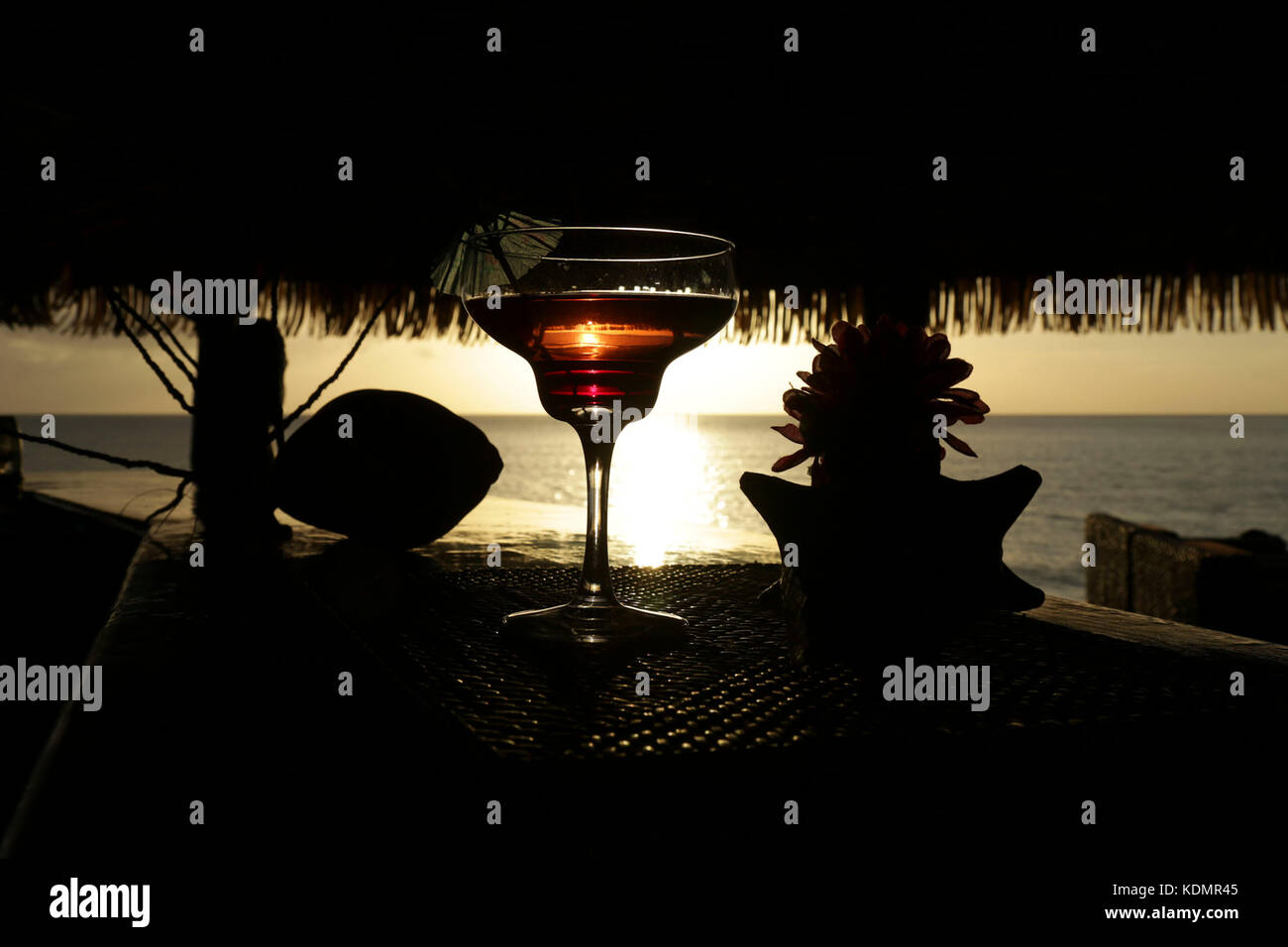 Bicchiere da cocktail con sullo sfondo il tramonto riflesso nel vetro. isola tropicale. Foto Stock