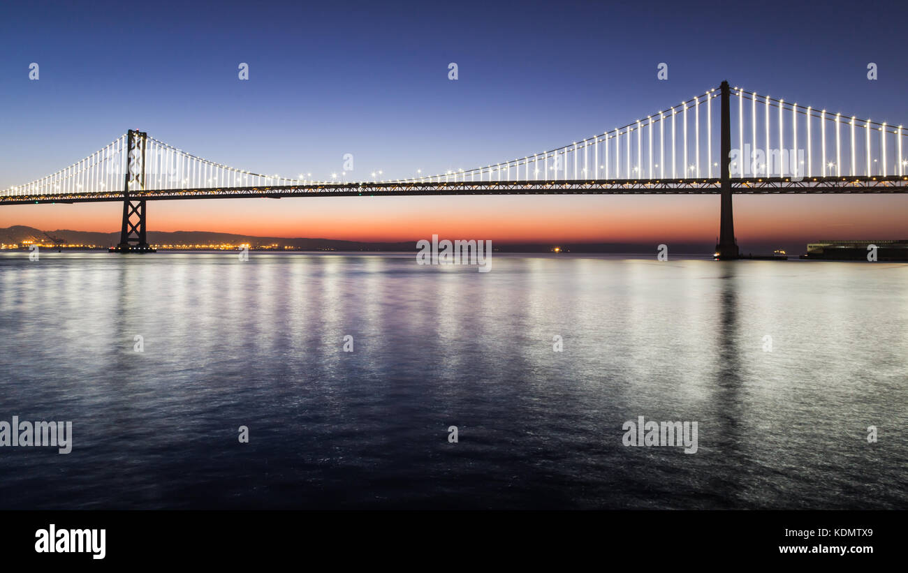 Il Bay Bridge luminarie riflessi nell'acqua da Pier 14, San Francisco. Foto Stock