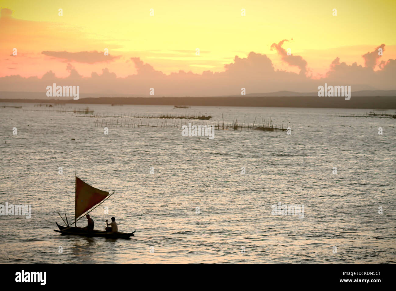 Silhouettes di pescatori in una vinta che è una tradizionale barca Outrigger delle isole Filippine di Mindanao, la vita quotidiana candida locale Foto Stock