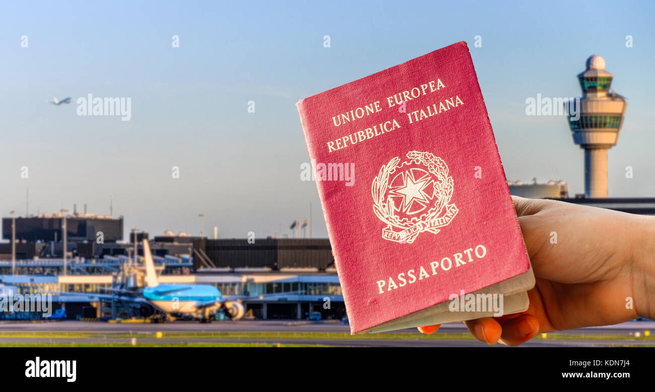 Composito digitale di mano con passaporto italiano con terminal aeroportuali affollato su sfondo sfocato Foto Stock