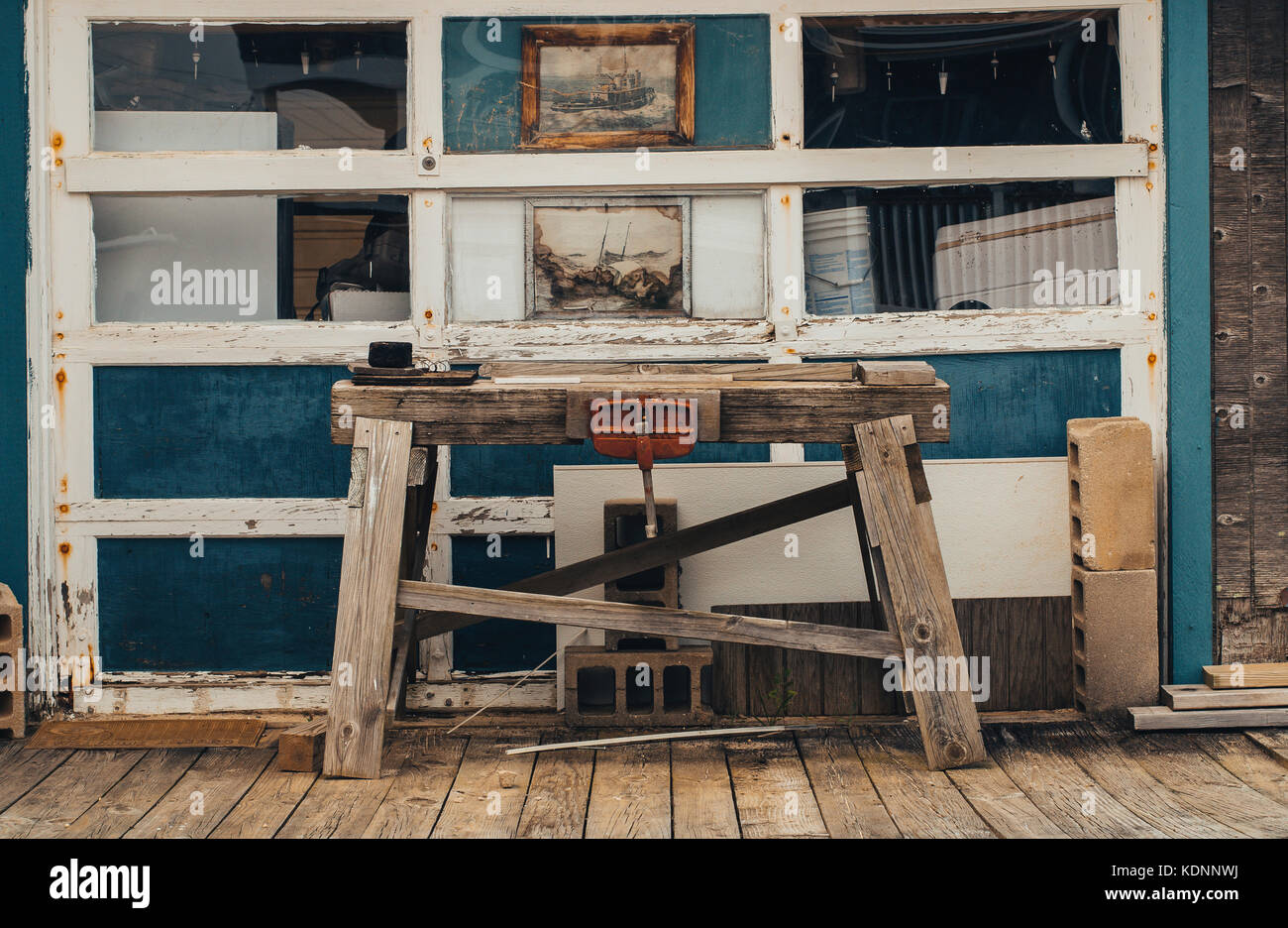 Rustico, banco di lavoro in legno con la fascetta nella parte anteriore di un confuso garage al Fisherman's cottage. Foto Stock