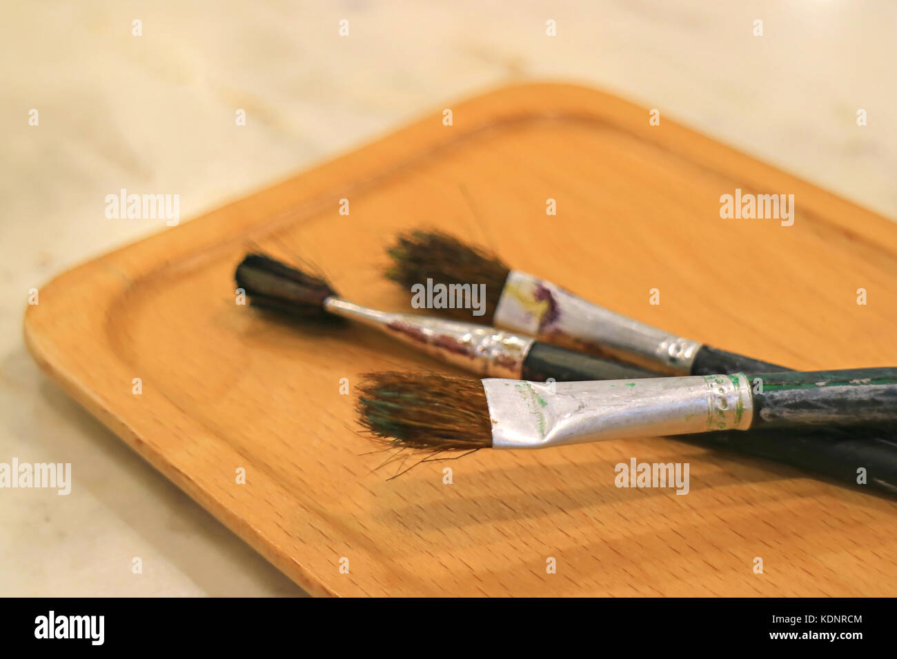 Tre pennelli per dipingere sul vassoio di legno sul tavolo Foto Stock