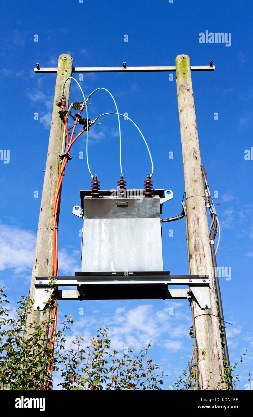 Un trasformatore elettrico montato tra due poli nella campagna inglese a Ringland, Norfolk, Inghilterra, Regno Unito. Foto Stock