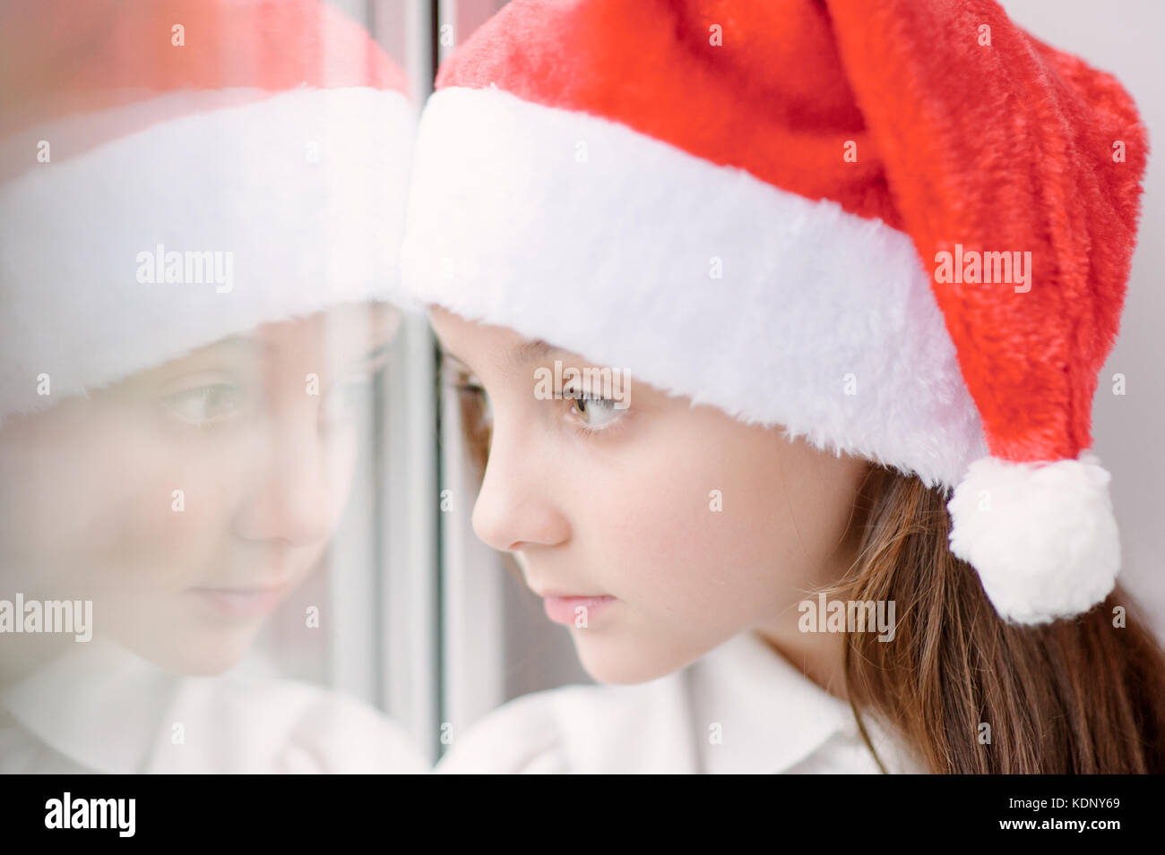 Adorabile bambina santa hat vicino alla finestra Foto Stock