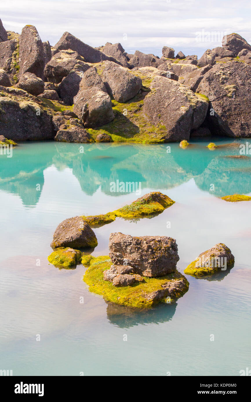 Boulder che sorge fuori del riflettente piscina verde, Stórurð (i giganteschi massi), Islanda Foto Stock