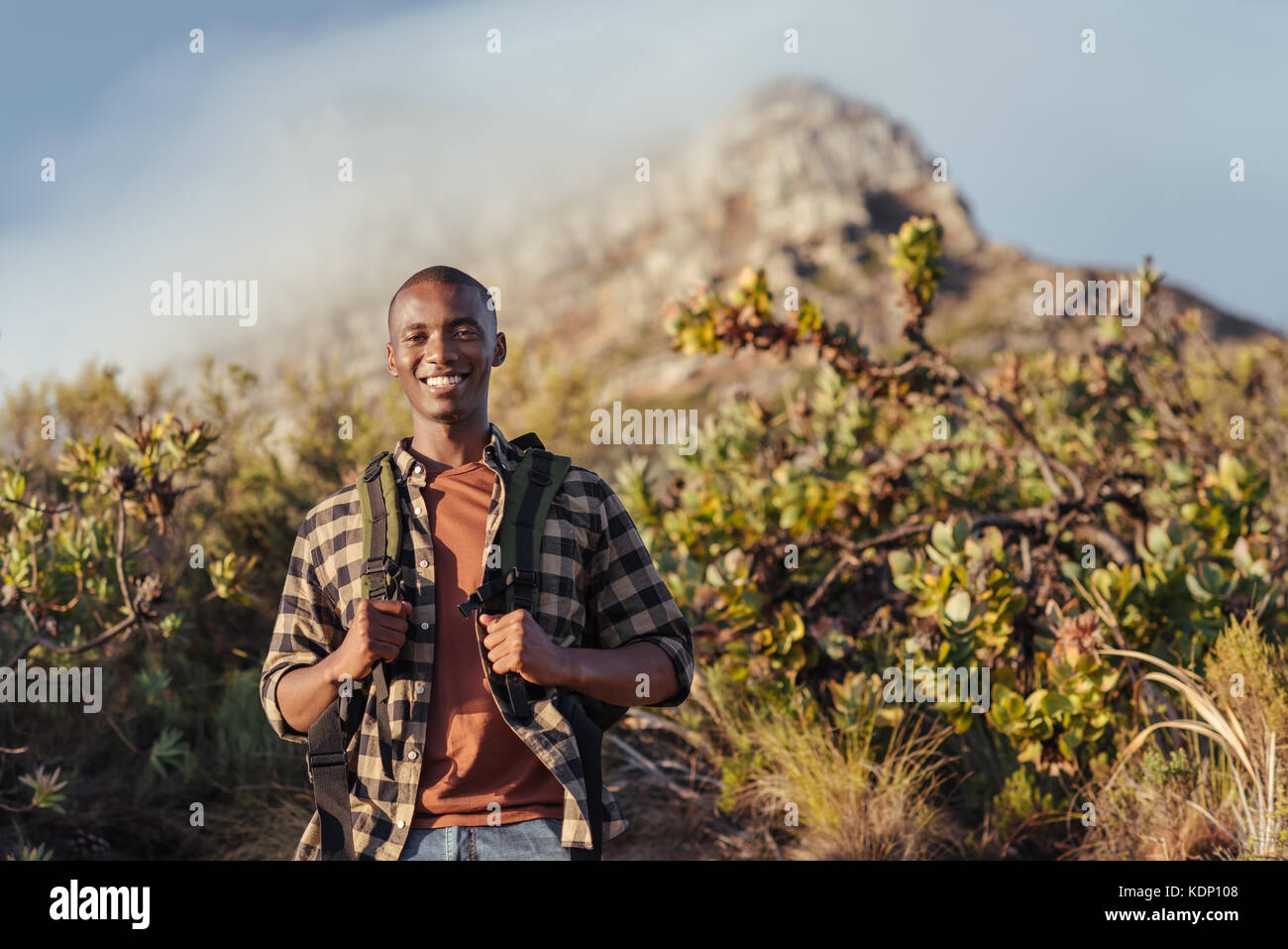 Sorridente giovane africano godendo di un trekking in montagna Foto Stock