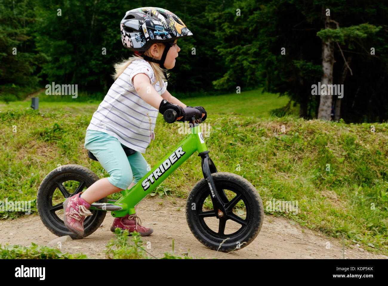 Una bambina di tre anni in sella a una moto di equilibrio Foto Stock