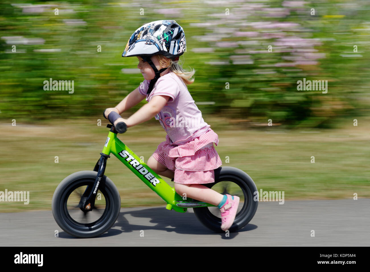 Una bambina di tre anni in sella a una moto di equilibrio Foto Stock