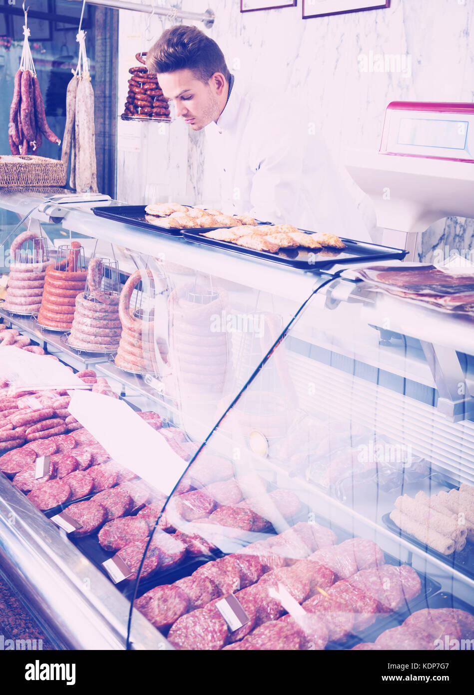 Negozio di positivo assistant in camice bianco al negozio di alimentari che mostra le carni fresche Foto Stock
