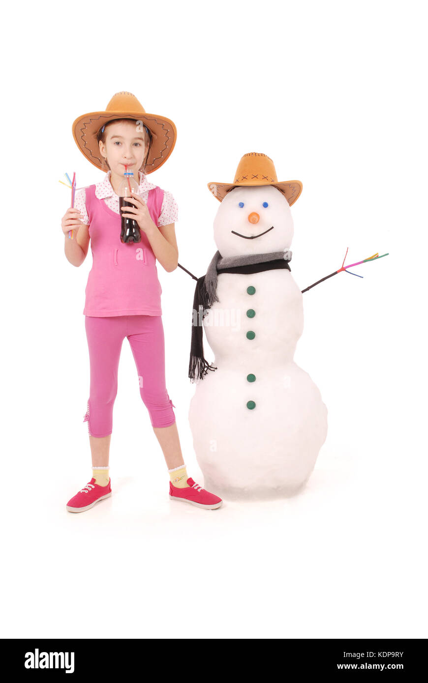 Carina ragazza con una bottiglia di cola nei pressi di un pupazzo di neve con sciarpa e cappello su sfondo bianco Foto Stock