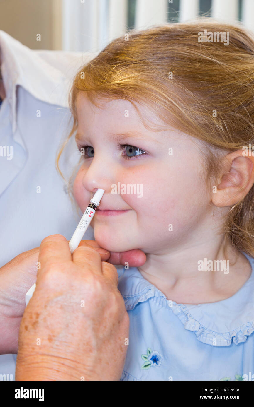 Bambino di 3 anni con la mamma / madre, riceve la dose di Fluenz vaccino antinfluenzale spray nasale immunizzazione dalla pratica di NHS nurse UK. (90) Foto Stock