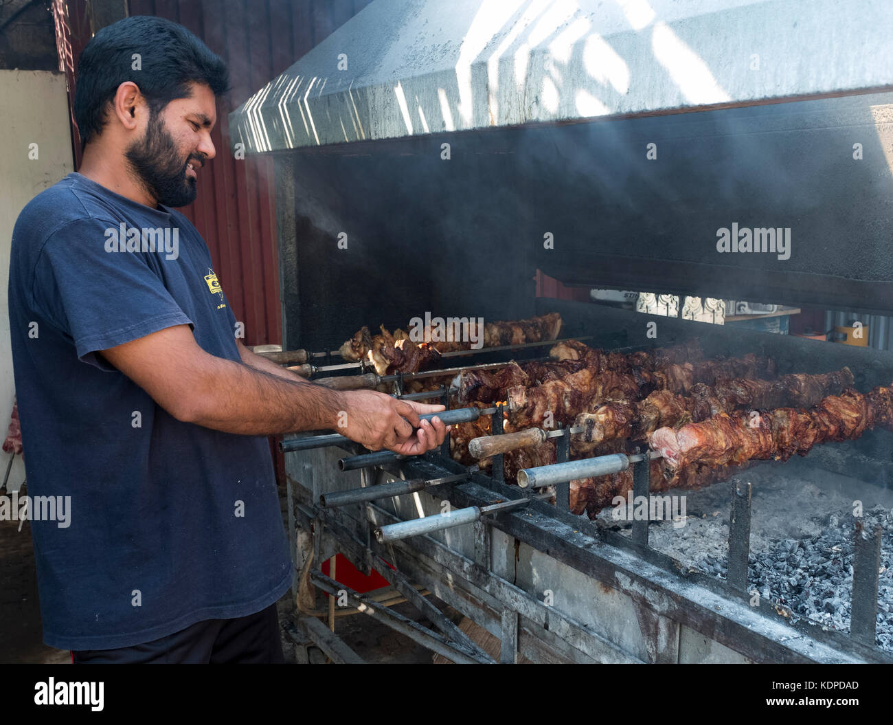 Membro dello staff la cottura di carne di maiale e di pollo su un barbecue presso l'ultimo castello ristorante, sulla penisola di Akamas, Peyia distretto, Paphos, Cipro. Foto Stock