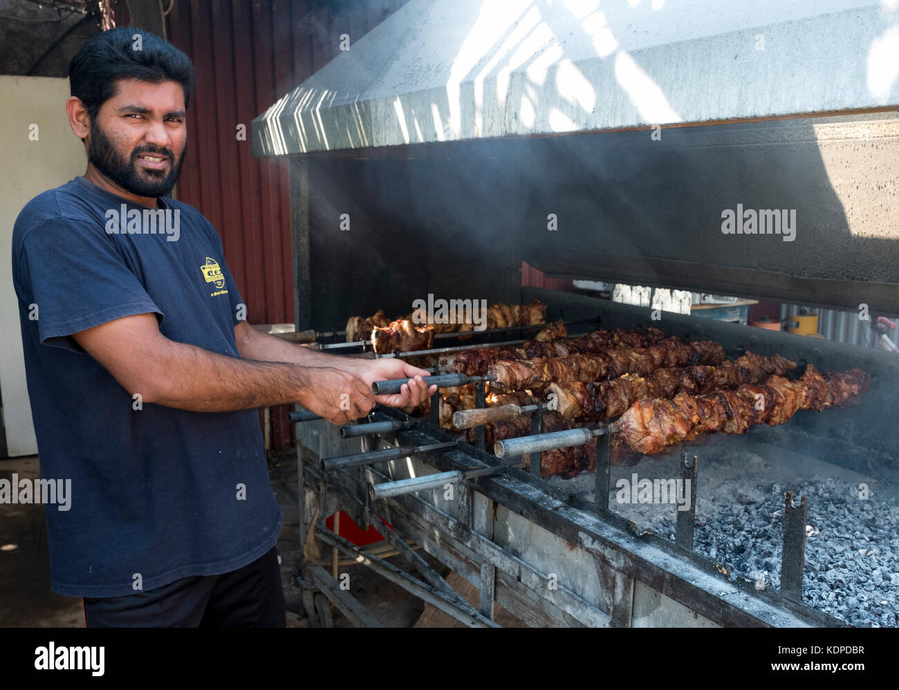 Membro dello staff la cottura di carne di maiale e di pollo su un barbecue presso l'ultimo castello ristorante, sulla penisola di Akamas, Peyia distretto, Paphos, Cipro. Foto Stock