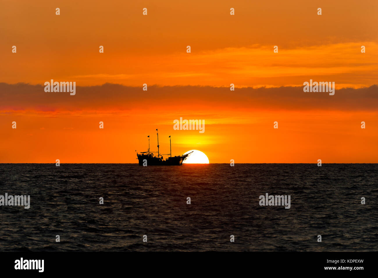 Nave Pirata silhouette è una nave pirata seduta sul mare guardando il tramonto sull'oceano stagliano contro il sole.. Foto Stock