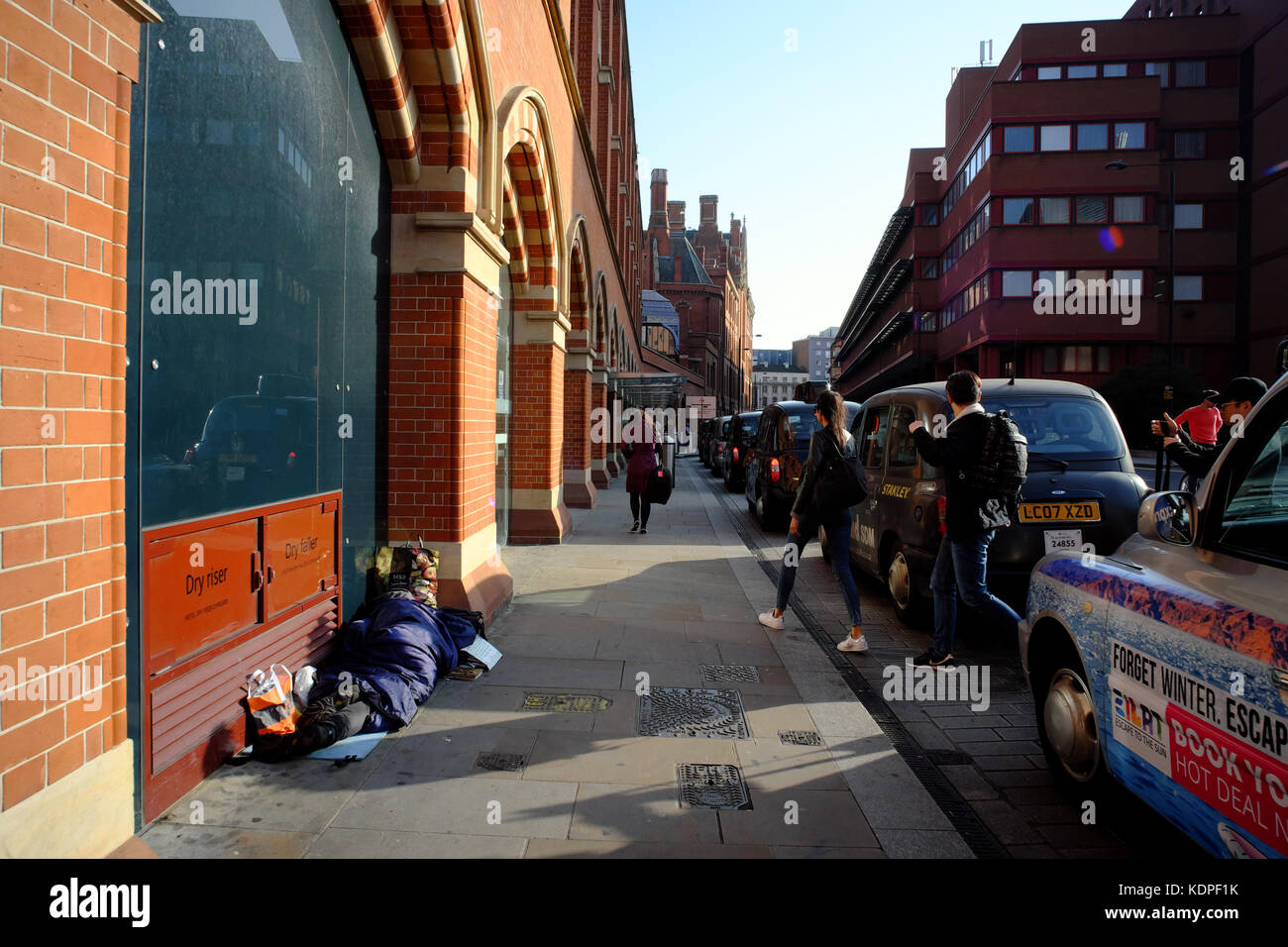 Taxi presso la stazione di St. Pancras & persona senzatetto che dorme sul marciapiede, Londra, Inghilterra Foto Stock