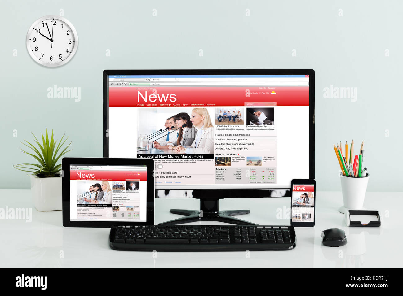Computer desktop con tavoletta digitale e mobilephone mostra online news sulla scrivania in ufficio Foto Stock