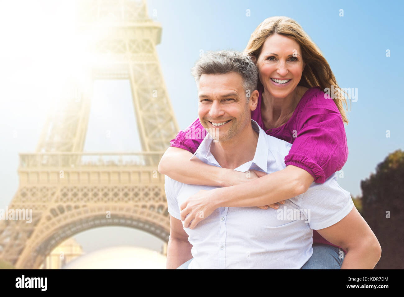 Ritratto di uomo felice piggybacking sua moglie vicino a torre eiffel Foto Stock